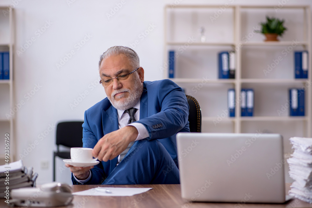 Old male employee drinking coffee during break Old male employee drinking coffee during break