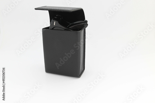 Black folding sunglasses in box case isolated on white background closeup.