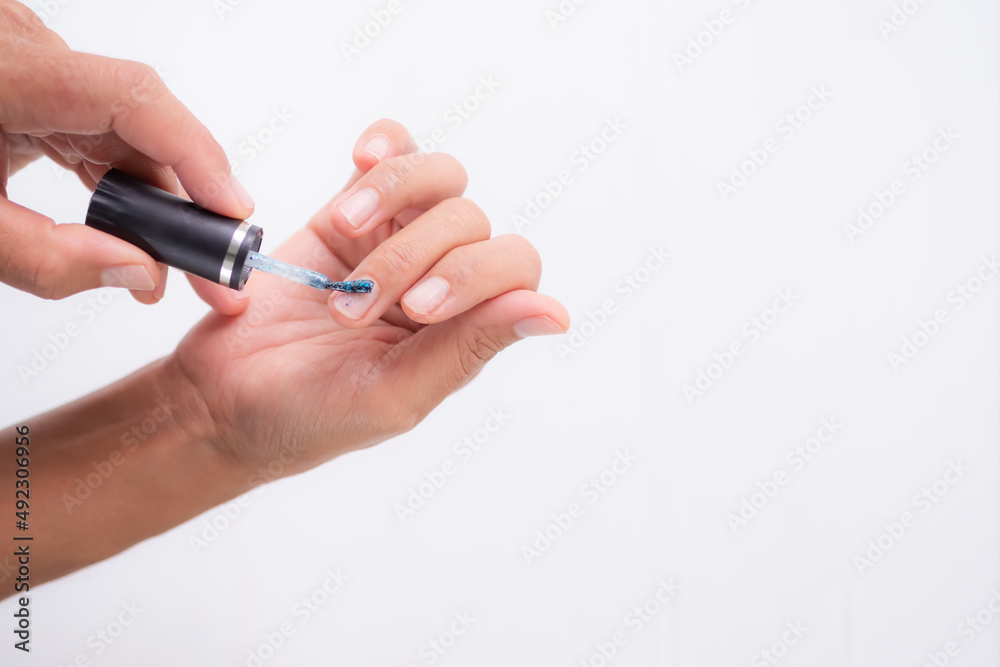 Woman holding paintbrush for nail polish close up on white background. green blue gel glamour.cosmetic makeup for beauty fashion concept. Woman holding paintbrush for nail polish close up on white background. green blue gel glamour.cosmetic makeup for beauty fashion concept.