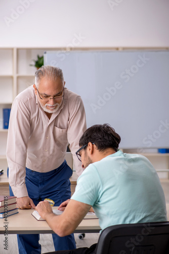 Old male teacher and young male student in the classroom