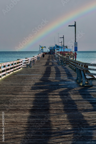 Person walking down a pier in Capitola  California with a rainbow in the distance