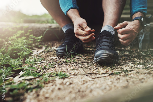 Adequate preparation plays the biggest role in ensuring safe travels. Close up shot of an unrecognizable man tying up his shoe laces on a hiking trail.
