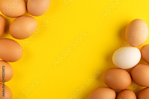 brown and white fresh farm eggs decoration for easter holiday on yellow background top view