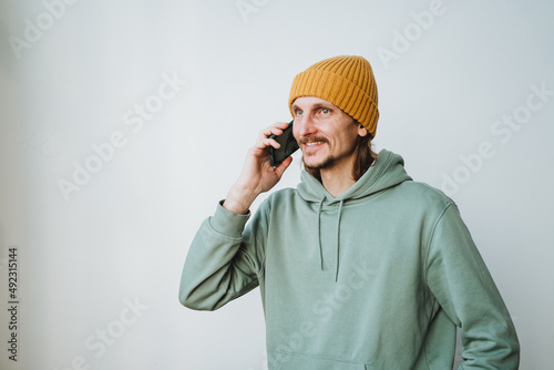 The man makes a phone call. A handsome young guy in casual clothes talks cheerfully on his mobile phone. Hipster smiles, a cheerful man.