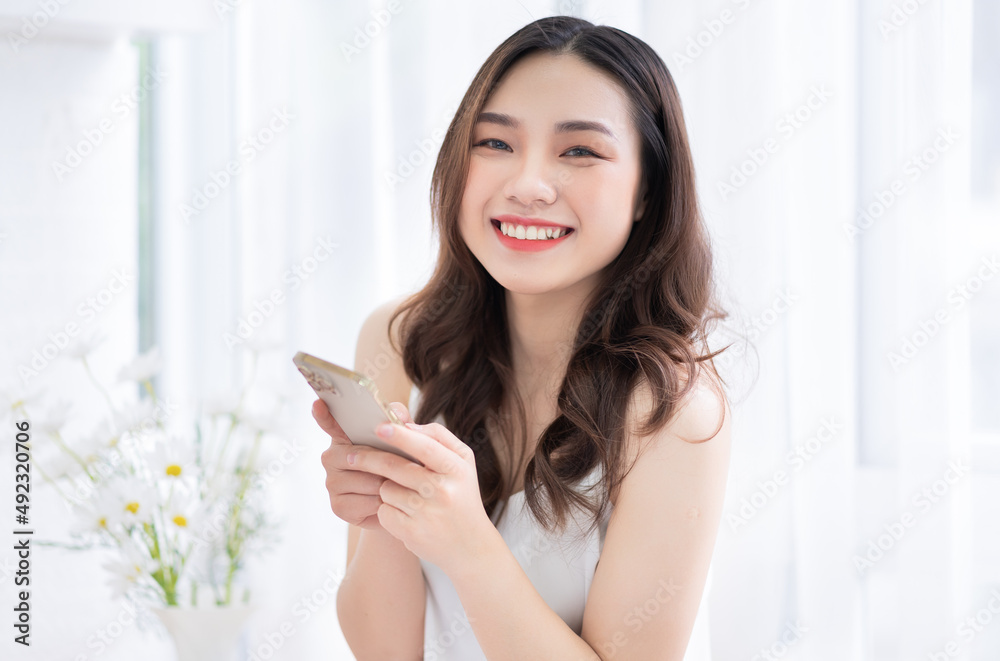 Young Asian woman using smartphone at home in the morning Young Asian woman using smartphone at home in the morning