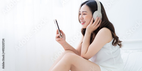 Image of young Asian woman listening music at home in the morning