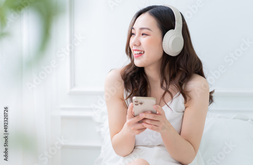 Image of young Asian woman listening music at home in the morning