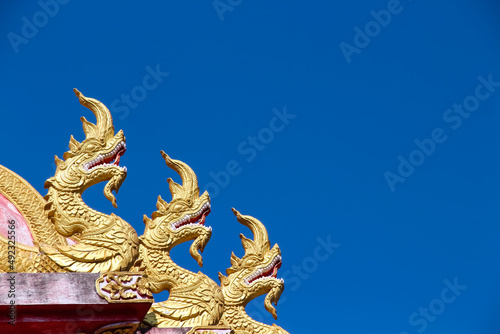 Gold yellow serpent  naga  patterns decorative on roof in Thail temple on bright blue sky background with vast space