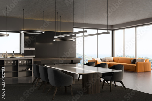 Dark studio interior with kitchen, sofa, panoramic window, dining table