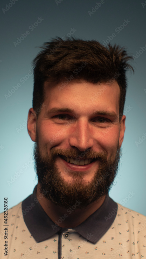 Young handsome man with beard wearing casual polo with anchors over blue background. Smiling relaxed and cheerful. Success and optimistic Young handsome man with beard wearing casual polo with anchors over blue background. Smiling relaxed and cheerful. Success and optimistic