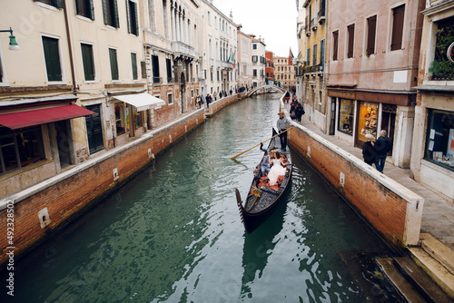 Gondolier rolls a bride and groom in a wooden gondola