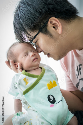 The father was nastily holding the newborn baby and sat beside a glass door with a curtain and white light. Give you a warm feeling