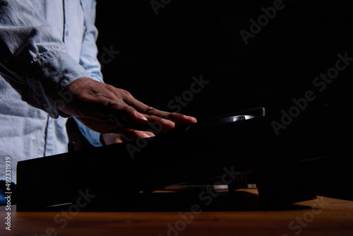 Close up of a black man's hand over a DJ console against a black background. African American man playing loud popular music in a club on professional music equipment