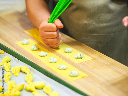 women chef hands preparing tortelli italian stuffed past with ricotta cheese and spinachs with organic eggs dough in a professional kitchen in Italy photo