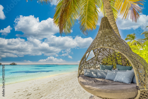 Tropical island beach as summer landscape with beach swing or hammock. Happy idyllic blue sky, sand palm tree leaves and calm sea beach. Couple romantic beach scene, vacation destination, traveling