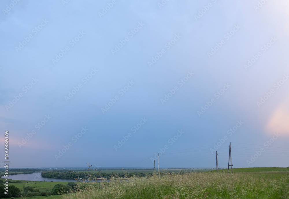 Obraz premium Summer landscape with meadow grass in the foreground. Blue sky before rain. Bright green grass.