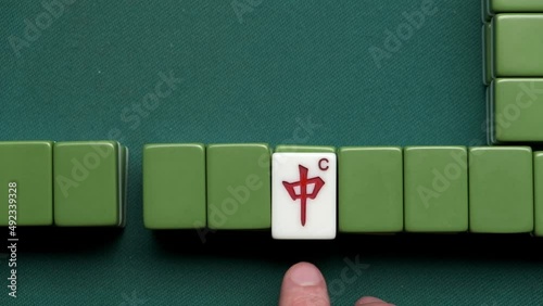 Mahjong game. Man rotate indicator of dora tile. Red dragon chun.