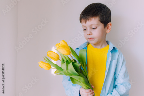 A boy with a bouquet of tulips lifestyle . Postcard for March 8. Congratulations on Women's Day. Congratulations on Mother's Day. Flowers are tulips.