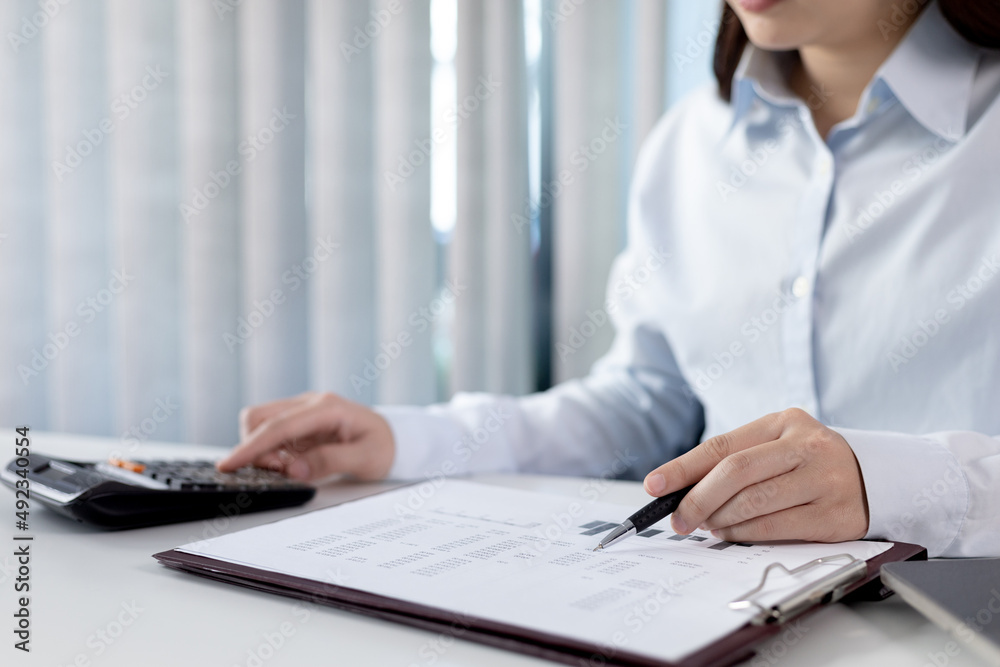 Businesswoman presses a calculator to calculate earnings and analyze company earnings in his private office, Information in finance and accounting, Company performance and revenue. Businesswoman presses a calculator to calculate earnings and analyze company earnings in his private office, Information in finance and accounting, Company performance and revenue.