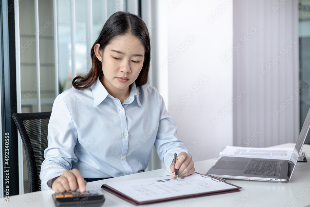 Businesswoman presses a calculator to calculate earnings and analyze company earnings in his private office, Information in finance and accounting, Company performance and revenue. Businesswoman presses a calculator to calculate earnings and analyze company earnings in his private office, Information in finance and accounting, Company performance and revenue.