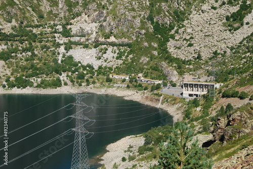 imagen de un lago entre montañas con unos cables eléctricos en el paisaje 