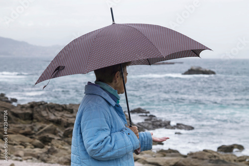 lonely woman with umbrella looking at the sea © tetxu