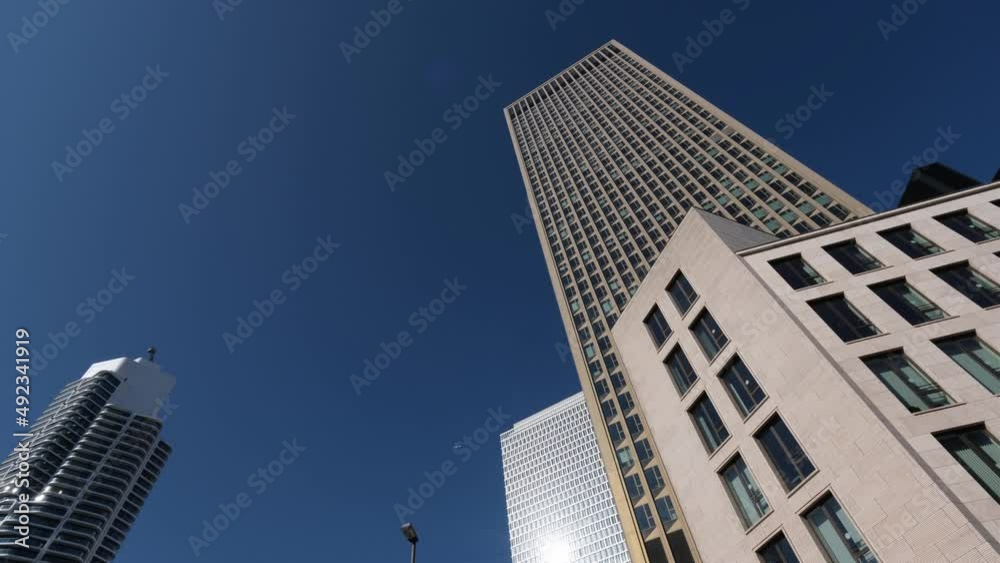 Skyscrapers of Frankfurt against the clear blue sky. There is an airplane with white trail line in the background. Looking up among tall buildings. City life, business, bank, trading concept. 4K Skyscrapers of Frankfurt against the clear blue sky. There is an airplane with white trail line in the background. Looking up among tall buildings. City life, business, bank, trading concept. 4K