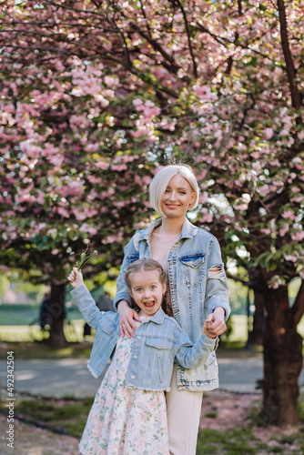 Sakura blossomed. Young mother with her child have fun in the park near the sakura. cherry trees blossom (Uzhhorod City, Ukraine)