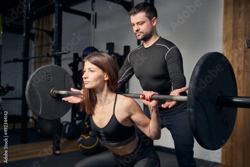 Woman having weight workout with make coach in gym