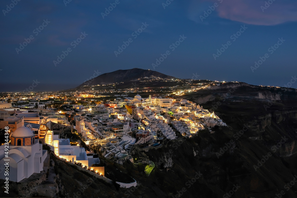Panoramic view of the picturesque illuminated village of Fira Santorini Greece at night time