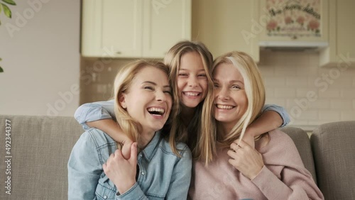three generations of women look at camera, cute little girl hug mom and granny enjoy time at home, smiling mother, daughter and grandmother