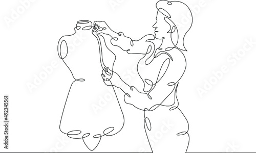 One continuous line.A fashion designer designs a dress. A seamstress works with a mannequin.Fashion designer, dressmaker, seamstress, sewing workshop or courses, tailoring concept. Continuous line dra
