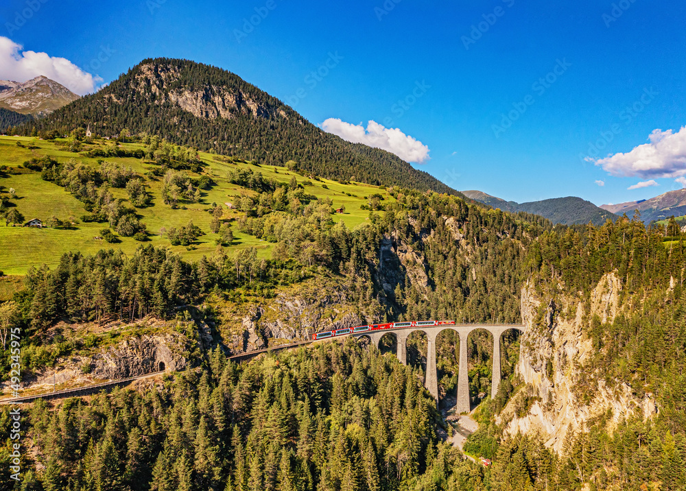 Glacier Express train on the famous Alpine route in Switzerland directly on the Landwasser viaduct bridge 
