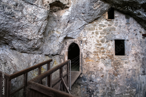 Predjama Castle in Slovenia. Interior of a castle hidden in a cave. Entrance to the fortification with a wooden bridge. photo