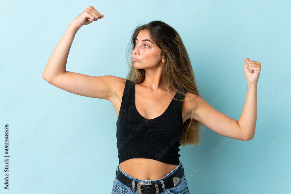 Young caucasian woman isolated on blue background doing strong gesture Young caucasian woman isolated on blue background doing strong gesture