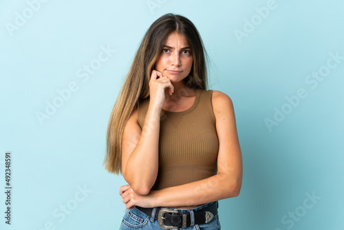 Young caucasian woman isolated on blue background having doubts and thinking
