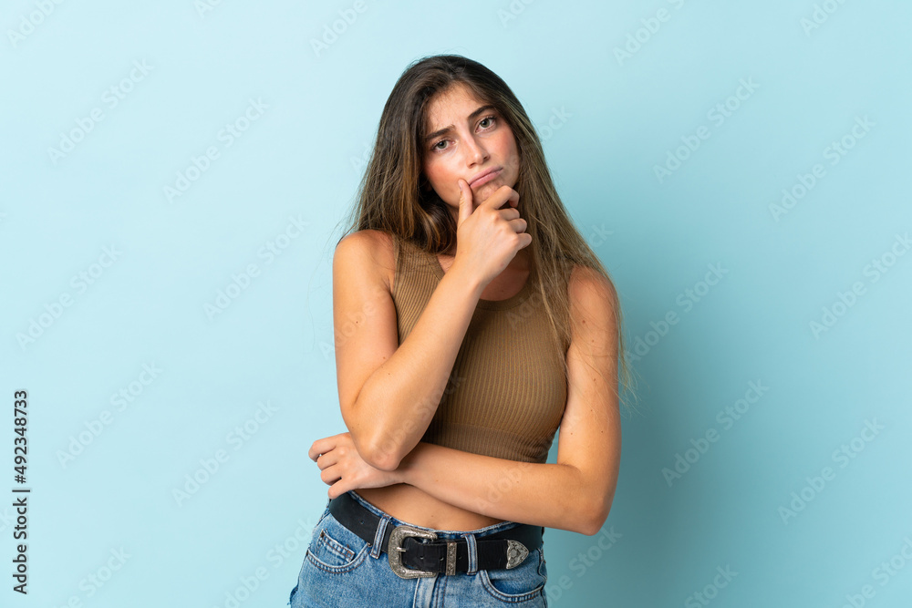 Young caucasian woman isolated on blue background having doubts Young caucasian woman isolated on blue background having doubts