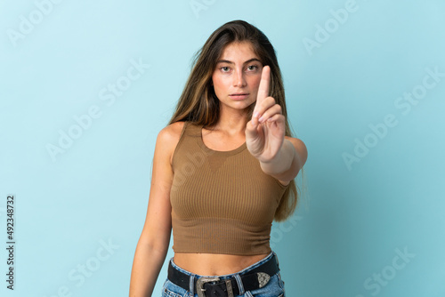 Young caucasian woman isolated on blue background counting one with serious expression