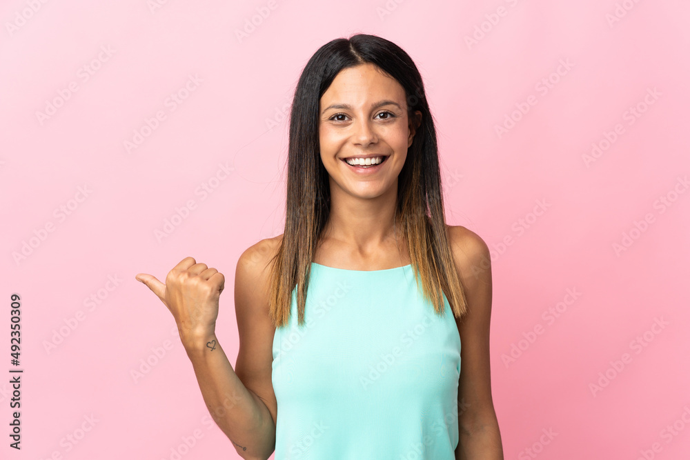 Caucasian girl isolated on pink background pointing to the side to present a product