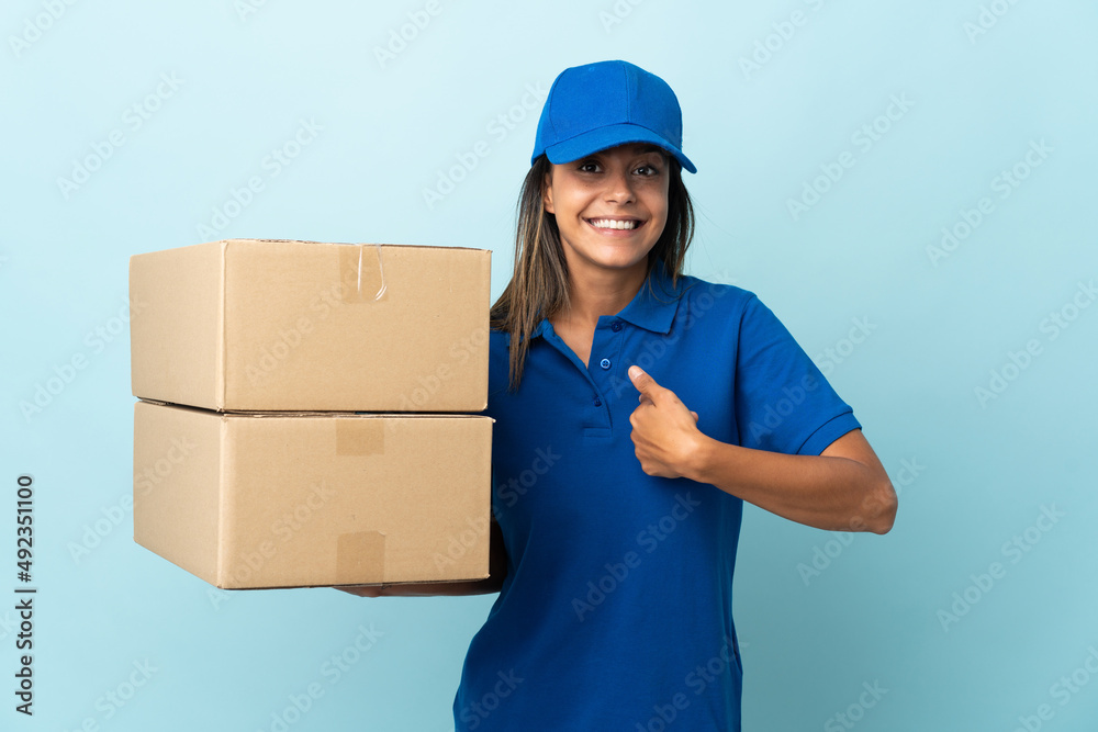 Young delivery woman isolated on blue background with surprise facial expression Young delivery woman isolated on blue background with surprise facial expression