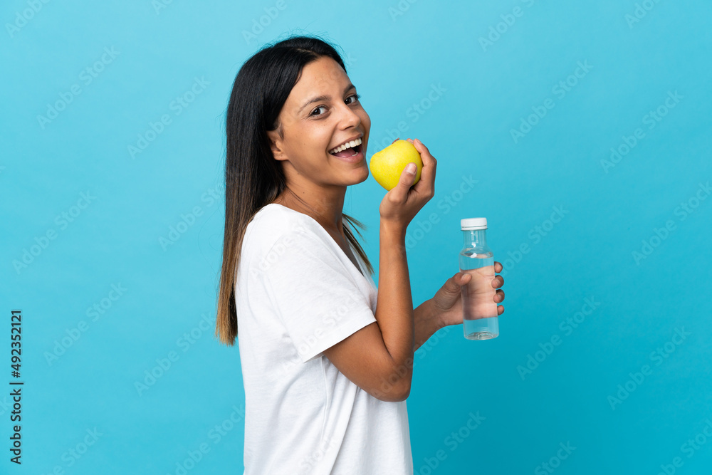 Caucasian girl isolated on blue background with an apple and with a bottle of water Caucasian girl isolated on blue background with an apple and with a bottle of water