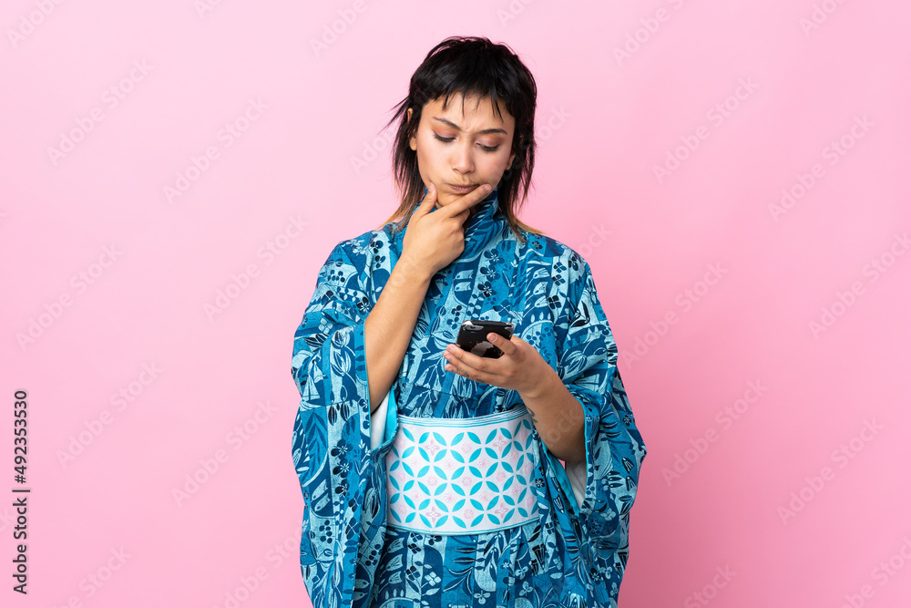 Young woman wearing kimono over isolated blue background thinking and sending a message
