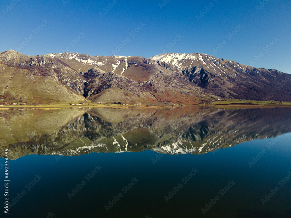 View of the mountain lake. Snowy mountains are displayed in a crystal clear lake. Lake Matese, province of Caserta Italy View of the mountain lake. Snowy mountains are displayed in a crystal clear lake. Lake Matese, province of Caserta Italy