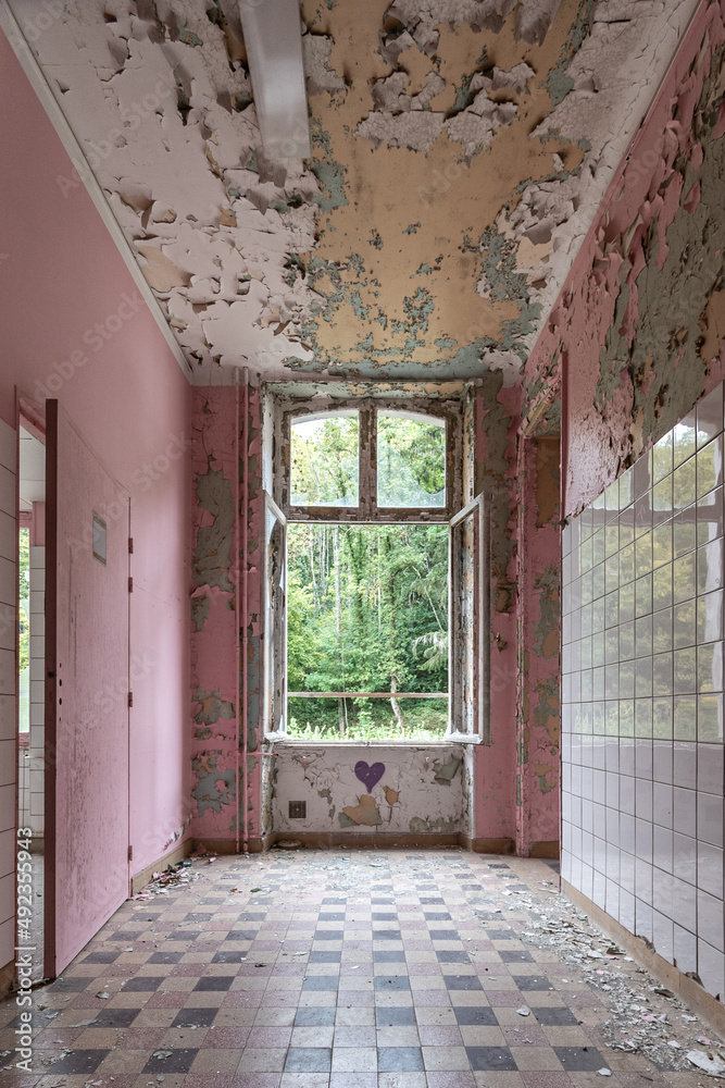 Corridor in an abandoned and run-down public accessible building, pink peeling paint on walls Corridor in an abandoned and run-down public accessible building, pink peeling paint on walls