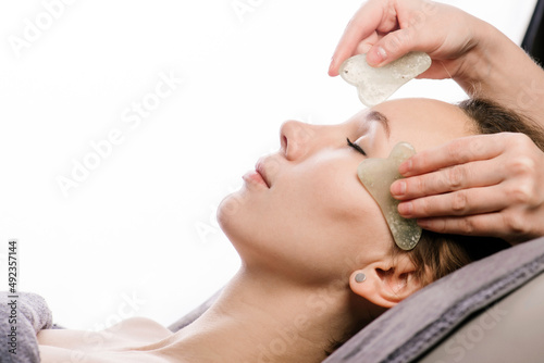 Gua sha massage of a woman in a beauty salon over white background.