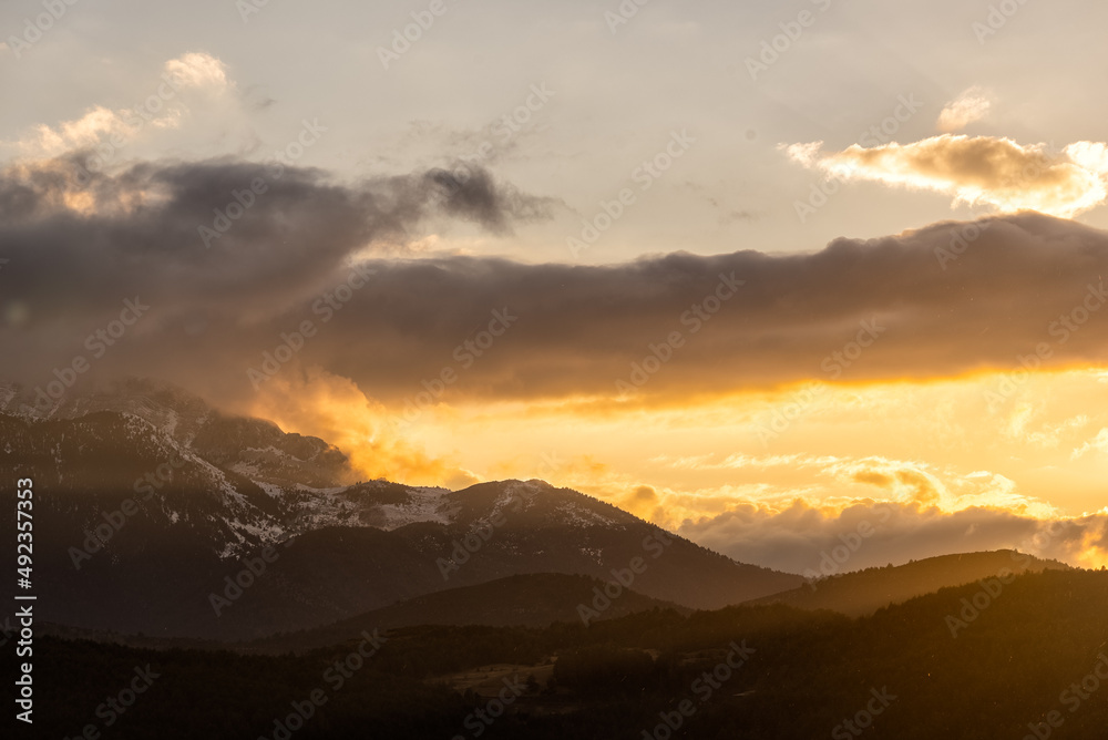 Amanecer soleado entre nubes en montaña con nieve