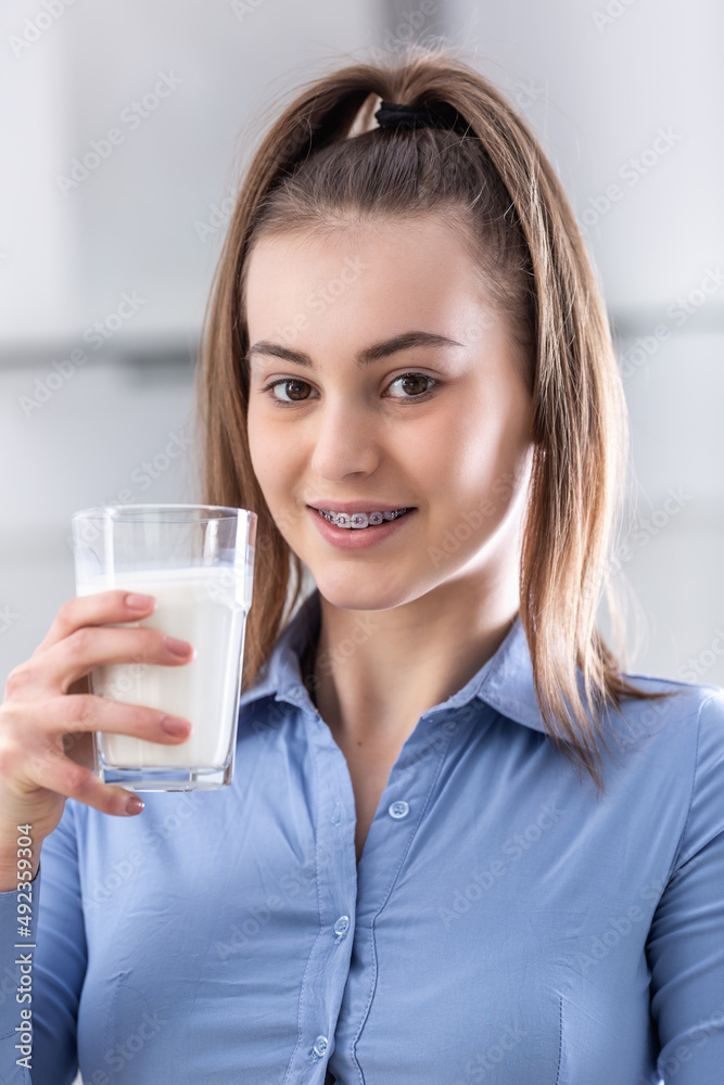 Young teenage girl with dental braces holding cup with milk Young teenage girl with dental braces holding cup with milk