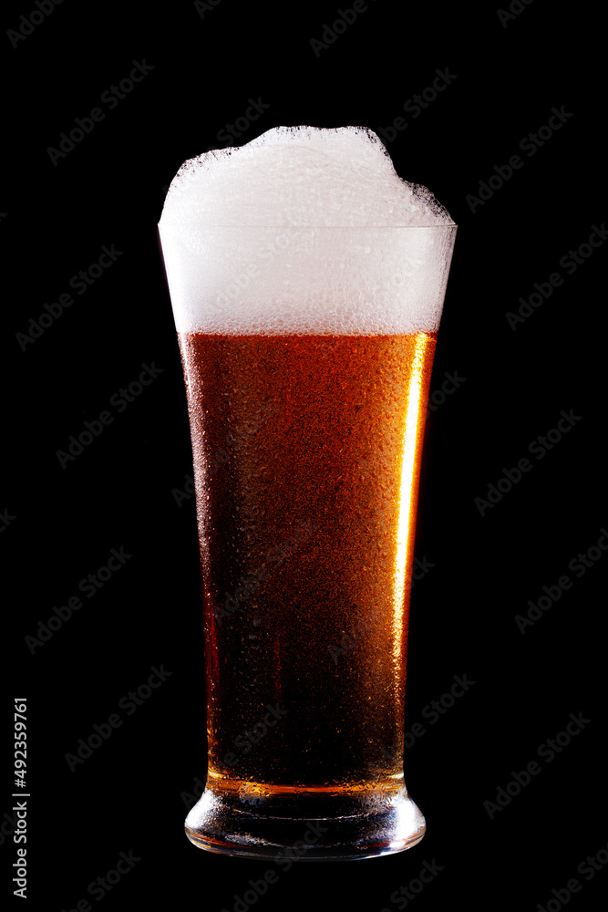 Glass of beer with foam on black background.t Glass of beer with foam on black background.t