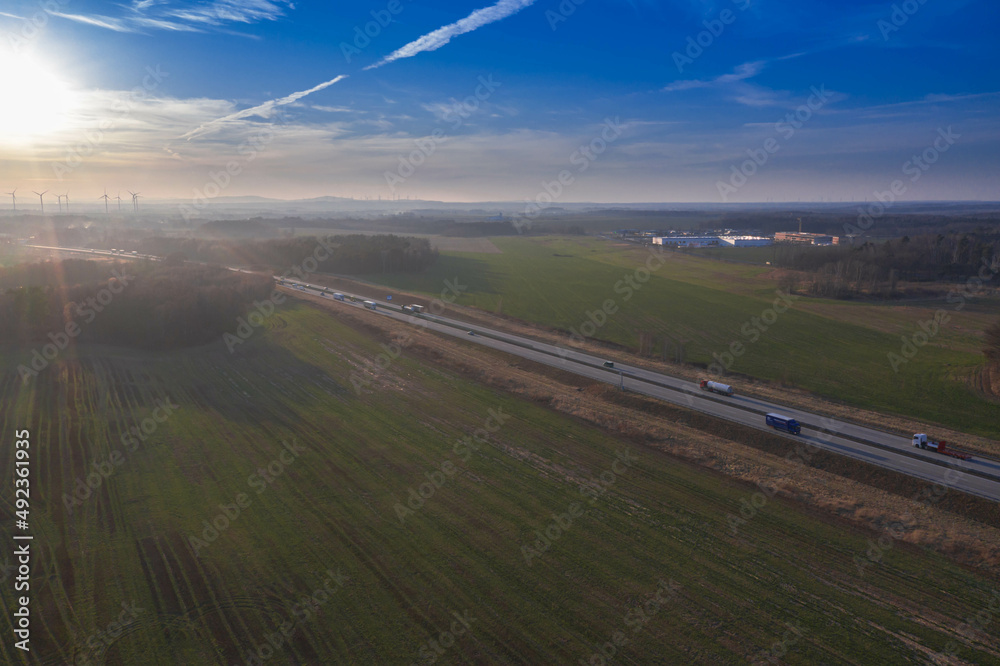 Droga przez równinę pokrytą łąkami i polami uprawnymi. Zdjęcie wykonano z dużej wysokości przy użyciu drona.