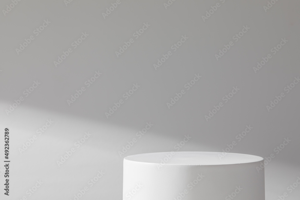 White cylindrical stone podium on a background of concrete wall